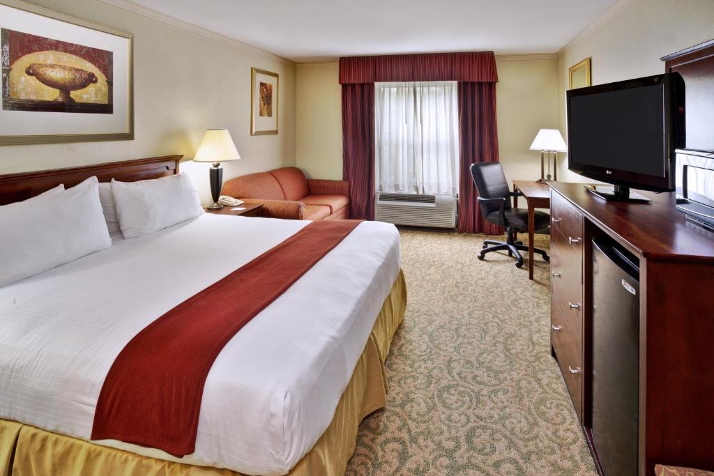 a hotel room with a bed and a flat screen tv at Holiday Inn Express Breaux Bridge, an IHG Hotel in Henderson