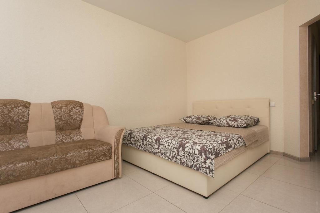 a bedroom with a bed and a couch at The Best Apartments Faraon on Kharkovskaya in Sumy