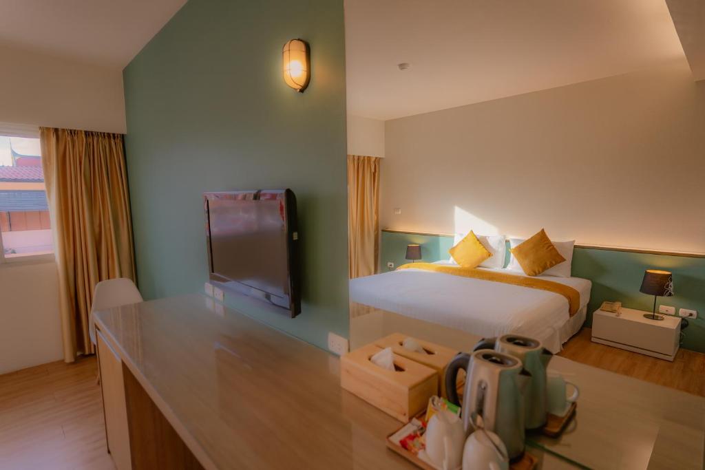 A bedroom photographed from the desk, with a large bed, television and tea-making setup.
