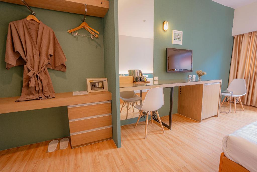 A bedroom view showing the bed edge, television, desk and open wardrobe together.