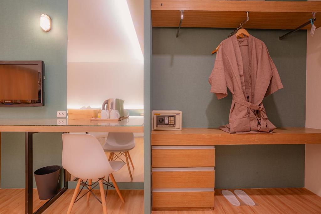 A compact hotel work-and-storage corner with a desk, safe and open wardrobe.