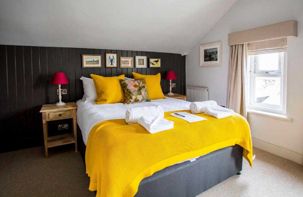 a bedroom with a yellow bed with towels on it at Dunstan House in Burnham on Sea