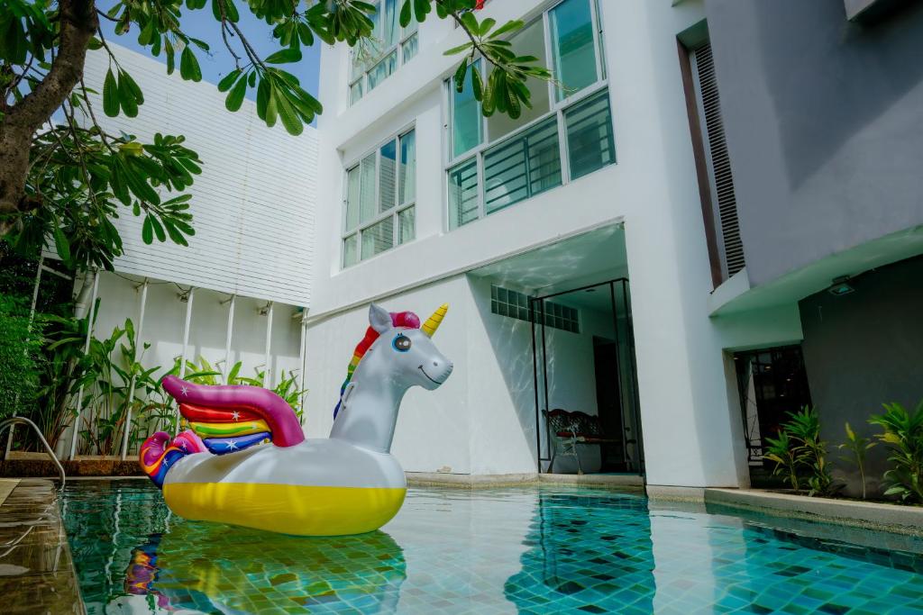 A courtyard pool is photographed with a colorful unicorn inflatable beneath surrounding hotel buildings.