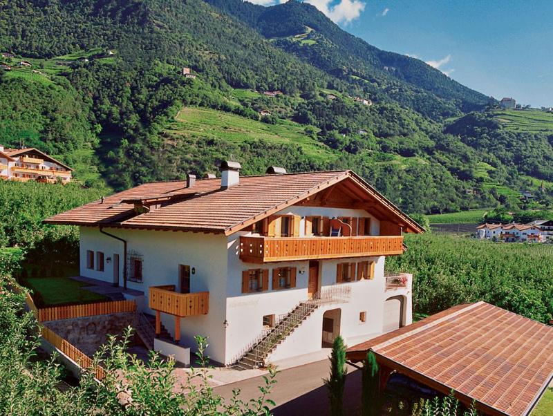 une maison sur une colline avec des montagnes en arrière-plan dans l'établissement Blummerhof, à Lagundo