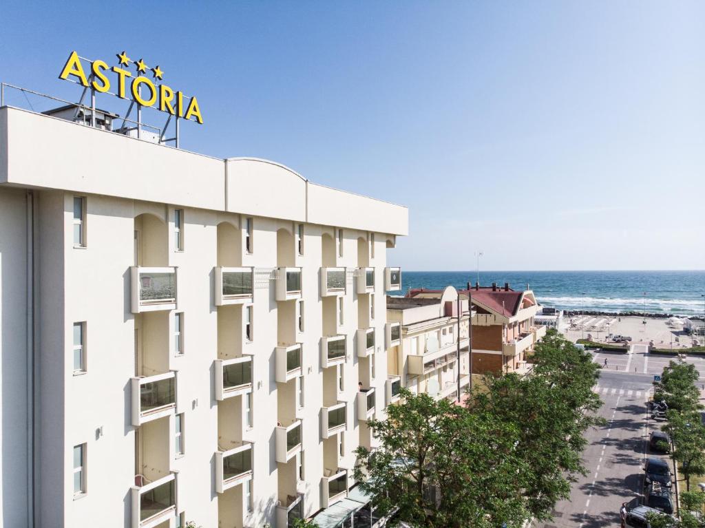 a building with a sign on top of it next to the ocean at Hotel Astoria in Misano Adriatico