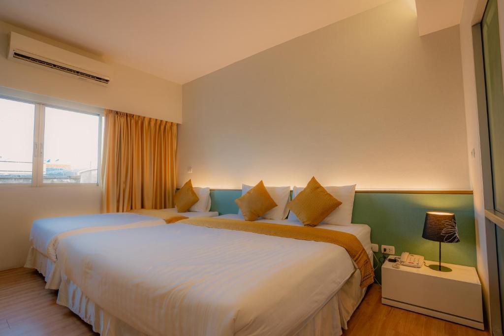 A twin room has two beds, a curtained window, bedside controls, and air-conditioning.