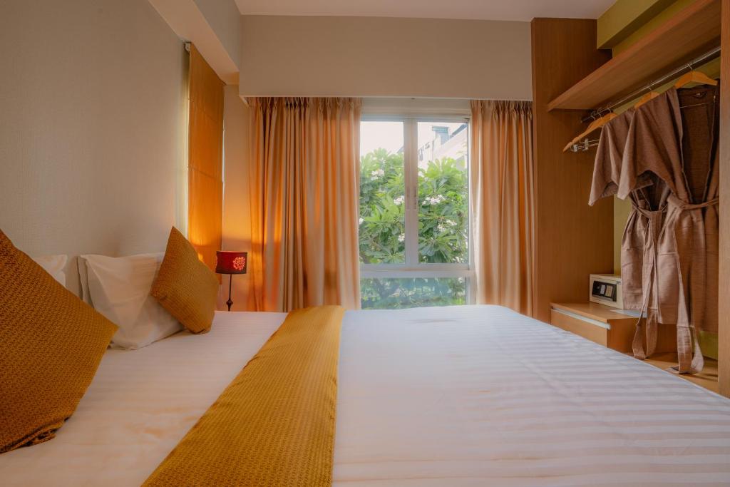 A double room looks toward a window with greenery and nearby buildings beyond.