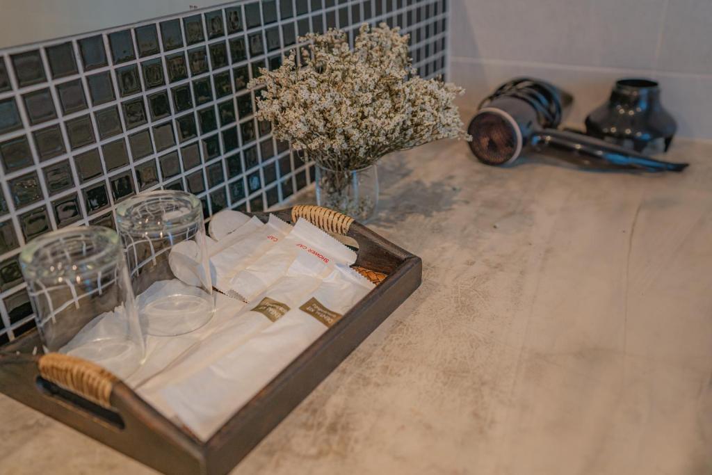 A bathroom counter styled with a tray of glasses, napkins and toiletries beside a faucet.