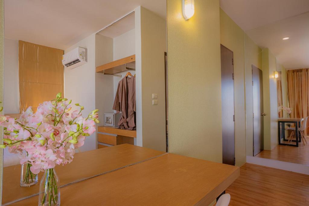 A wooden room console styled with flowers, beside open storage and a mirrored hallway.