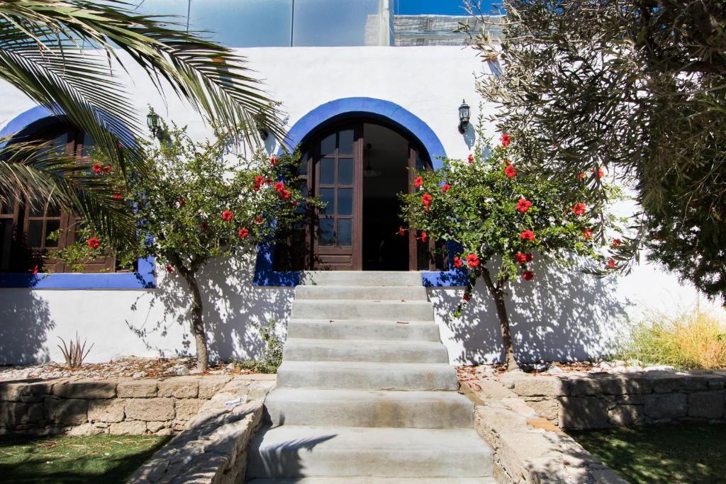 a stairway leading up to a house with red flowers at Poseidon Blue Gastronomy Hotel in Afiartis