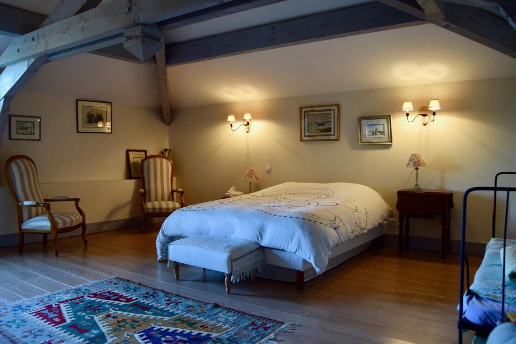 a bedroom with a bed and two chairs at Les Écuries de Saint Sever in Saint-Sever