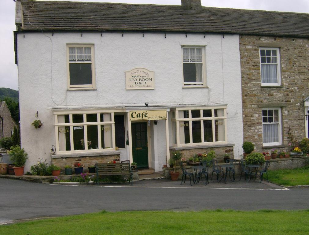 Un edificio blanco con mesas y sillas delante. en Ivy Cottage Bed & Breakfast, en Reeth
