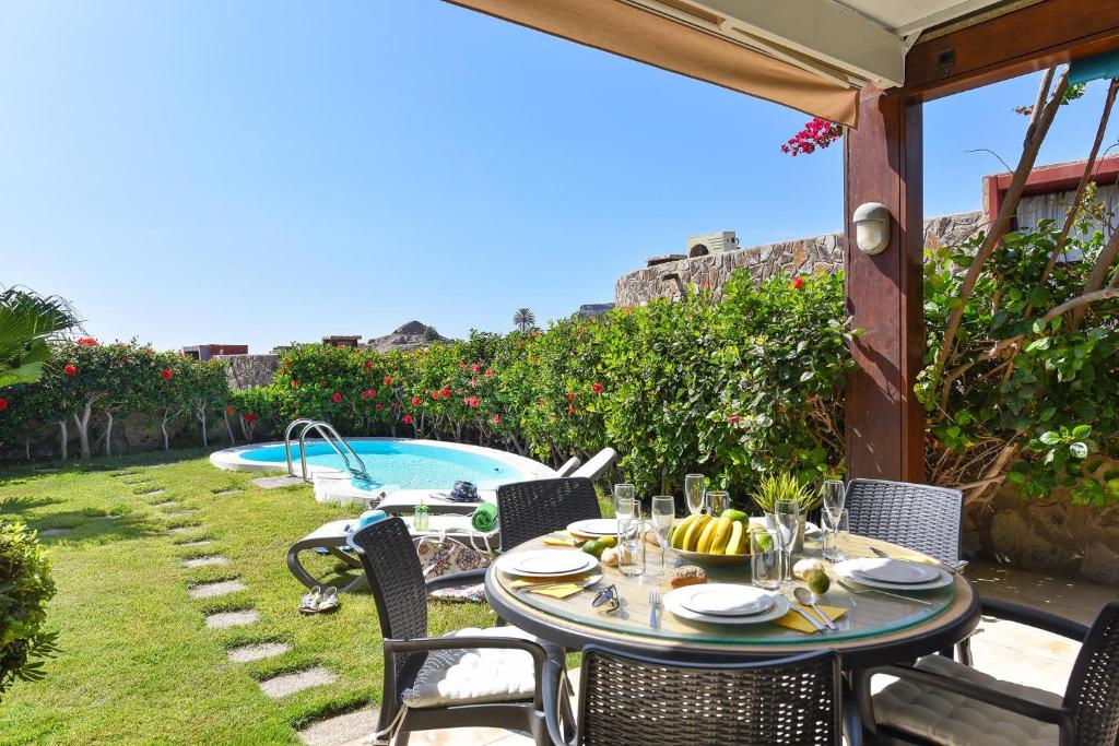 un patio avec une table et des chaises à côté d'une piscine dans l'établissement Tauro Golf by VillaGranCanaria, à Puerto Rico