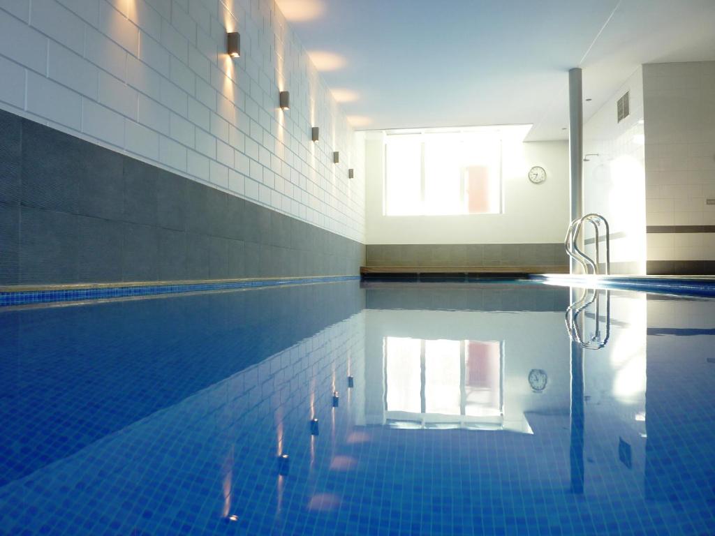 a swimming pool with a blue tile floor and a swimming pool at Inblauw - Exclusive Wellness B&B in Leuven