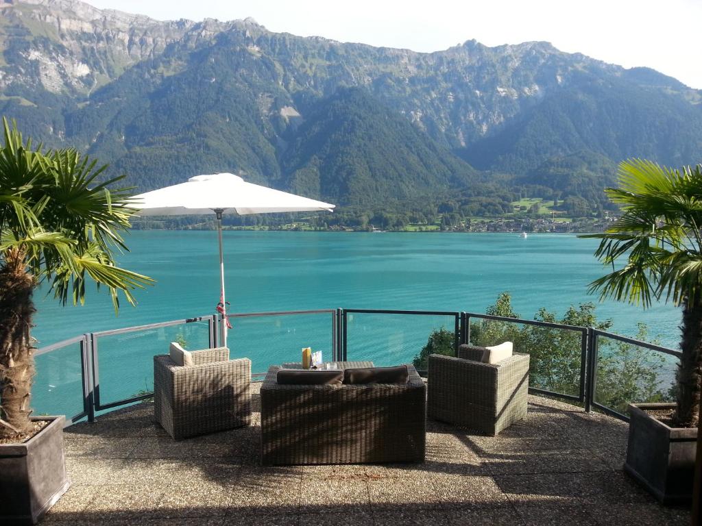 um pátio com cadeiras e um guarda-sol e um corpo de água em Hotel Brienzersee em Ringgenberg