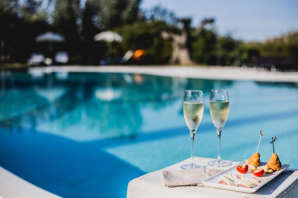 two glasses of white wine next to a swimming pool at Hotel Aquadulci in Chia