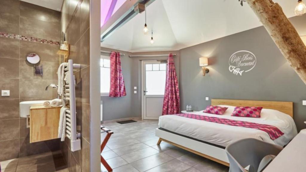 a bedroom with a king sized bed and a bathroom at Le Manoir d'à Côté in Courseulles-sur-Mer