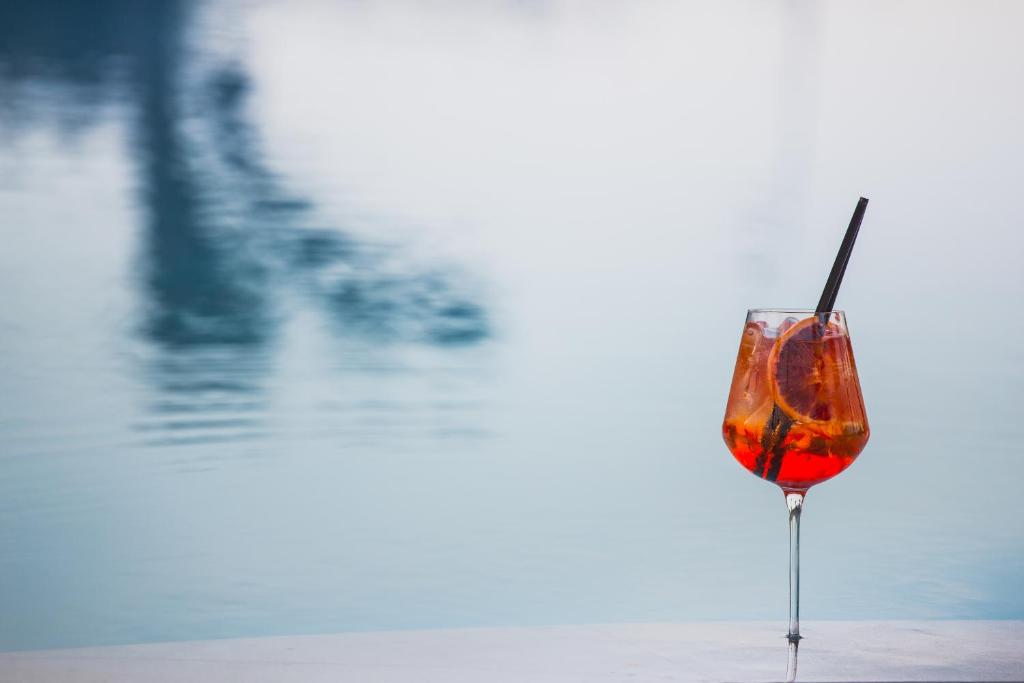a glass of wine sitting next to a body of water at Hotel Aquadulci in Chia