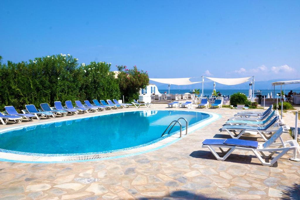 a large swimming pool with lounge chairs and a poolvisorvisorvisor at Erosea Beach Resort in Kavos