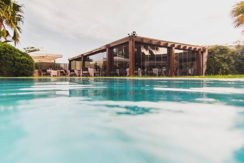 a swimming pool with a building in the background at Hotel Aquadulci in Chia