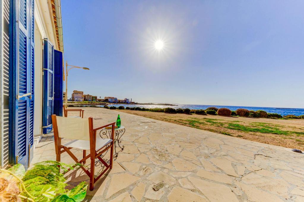 a chair sitting on a patio looking at the beach at Beachfront Apartment Migjorn Playa in Colònia de Sant Jordi