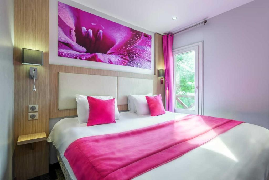 a bedroom with a large bed and a painting on the wall at Comfort Hotel Orléans Sud Co'met in Orléans