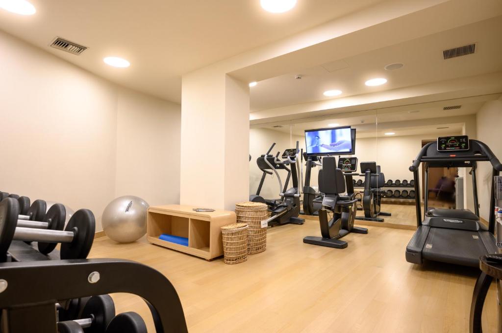 a gym with treadmills elliptical machines and a flat screen tv at Somewhere Vouliagmeni in Athens