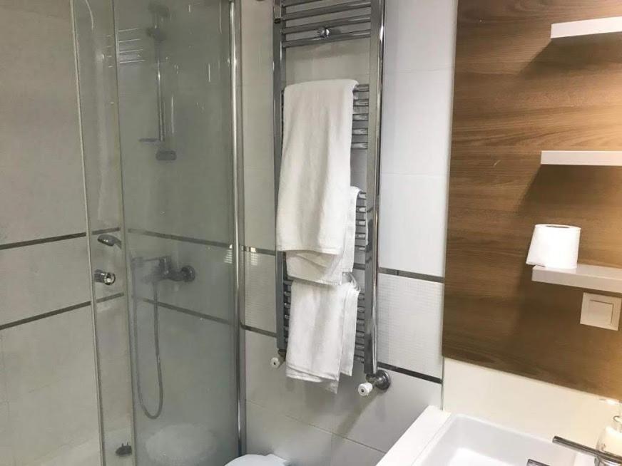 uma casa de banho com chuveiro e toalhas brancas em medikule 3 em Istambul