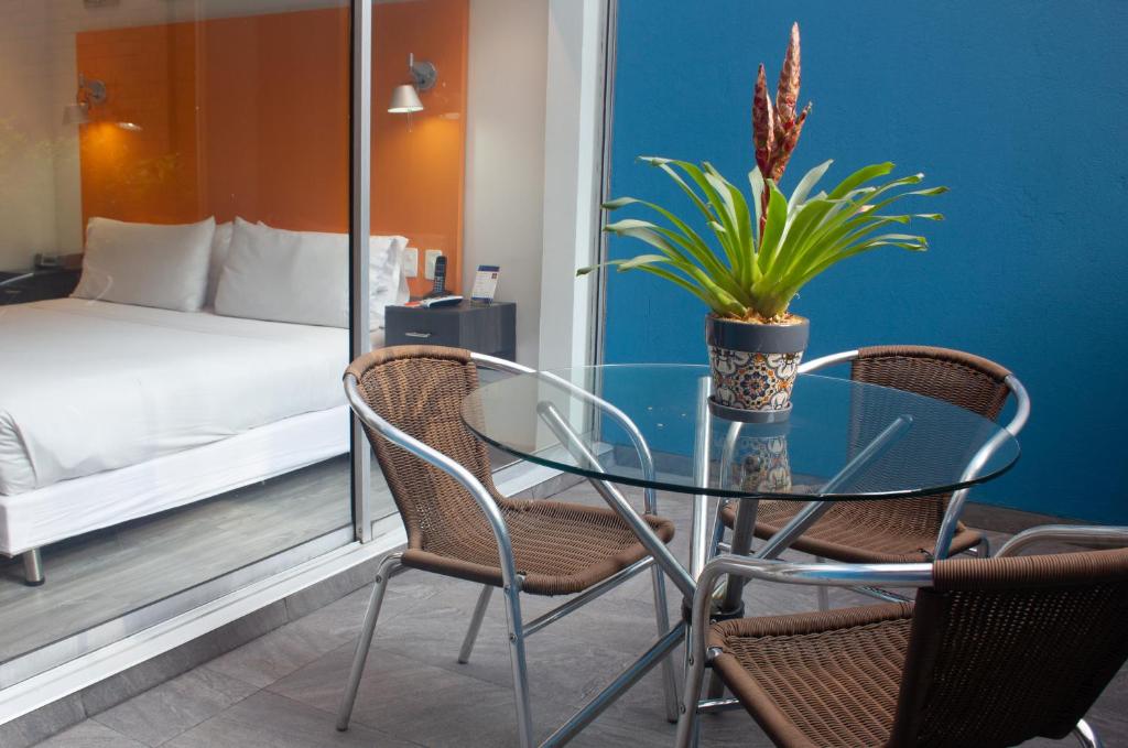 een glazen tafel met twee stoelen en een potplant bij Hotel 104 Art Suites in Bogota
