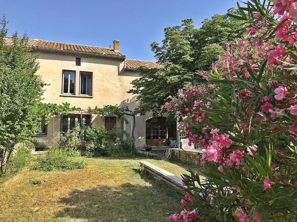 een huis met roze bloemen ervoor bij Le Clos de l'Apparent in Rochegude