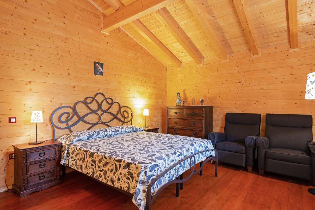 a bedroom with a bed and two chairs at Chalet Scordapeni in Santa Maria di Licodia
