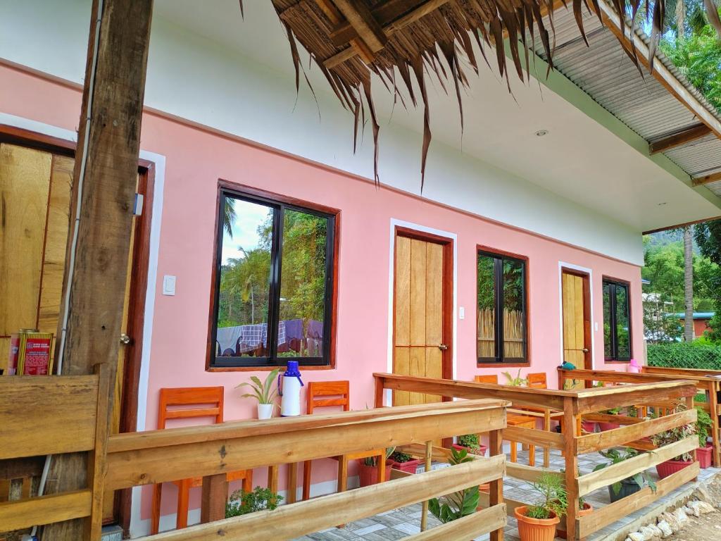 a pink house with wooden benches and windows at NoBi's Inn, Port Barton in San Vicente