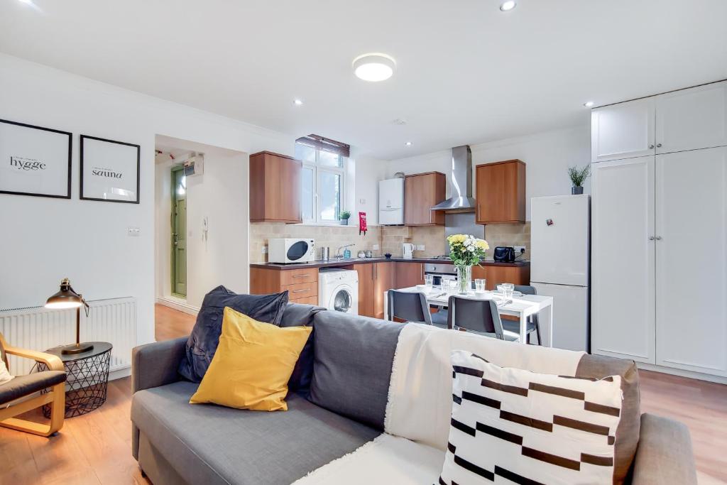 a living room with a couch and a kitchen at WelcomeStay Tooting Broadway 3 Bedroom Apartment in London
