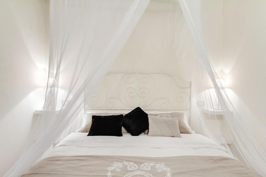 un letto bianco con tende bianche e cuscini neri di Elegant Apartment Behind the Colosseum a Roma