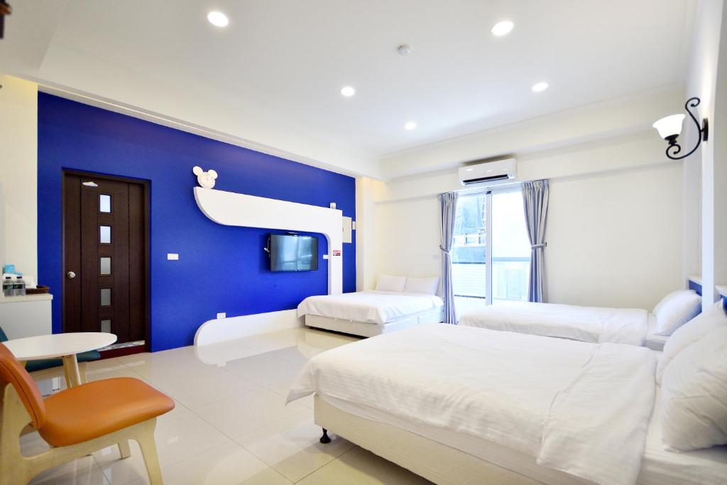 ein Schlafzimmer mit zwei Betten und einer blauen Wand in der Unterkunft Kai Feng B&B in Taitung