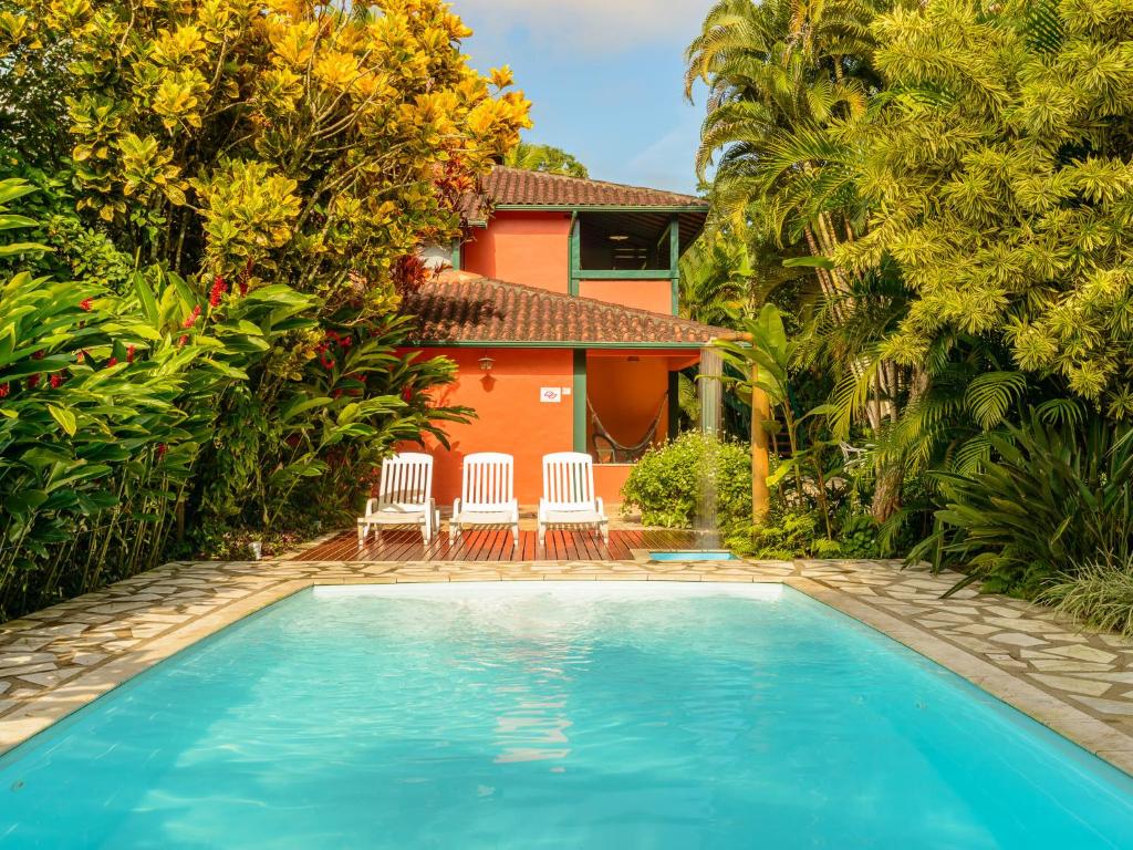 a swimming pool with two chairs and a house at Pousada Ecoilha in Ilhabela