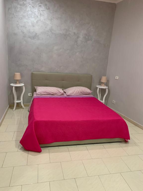 1 dormitorio con 1 cama rosa y 2 mesas en Casa Toto, en Nápoles