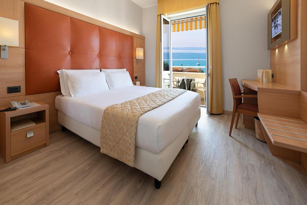 バルドリーノにあるHotel GARDENIA & Villa CHARME Adults Friendly 10Plusのベッド、デスク、窓が備わるホテルルームです。