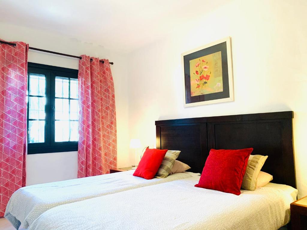 a bedroom with two beds with red pillows at Tagoror Lanzarote in Puerto del Carmen