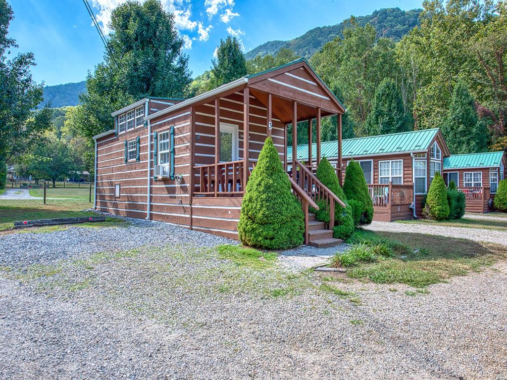 Cabaña de madera pequeña con escalera en la entrada en Maggie Valley Cabin Rentals, en Maggie Valley