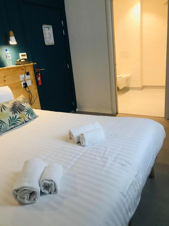 a bedroom with a bed with towels on it at Hôtel Café Miramar in Le Grau-du-Roi