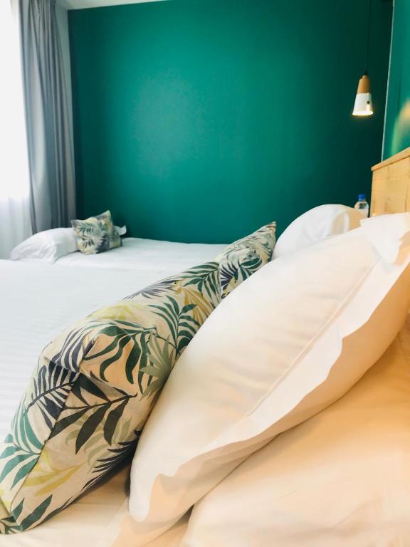 two beds in a room with a green wall at Hôtel Café Miramar in Le Grau-du-Roi