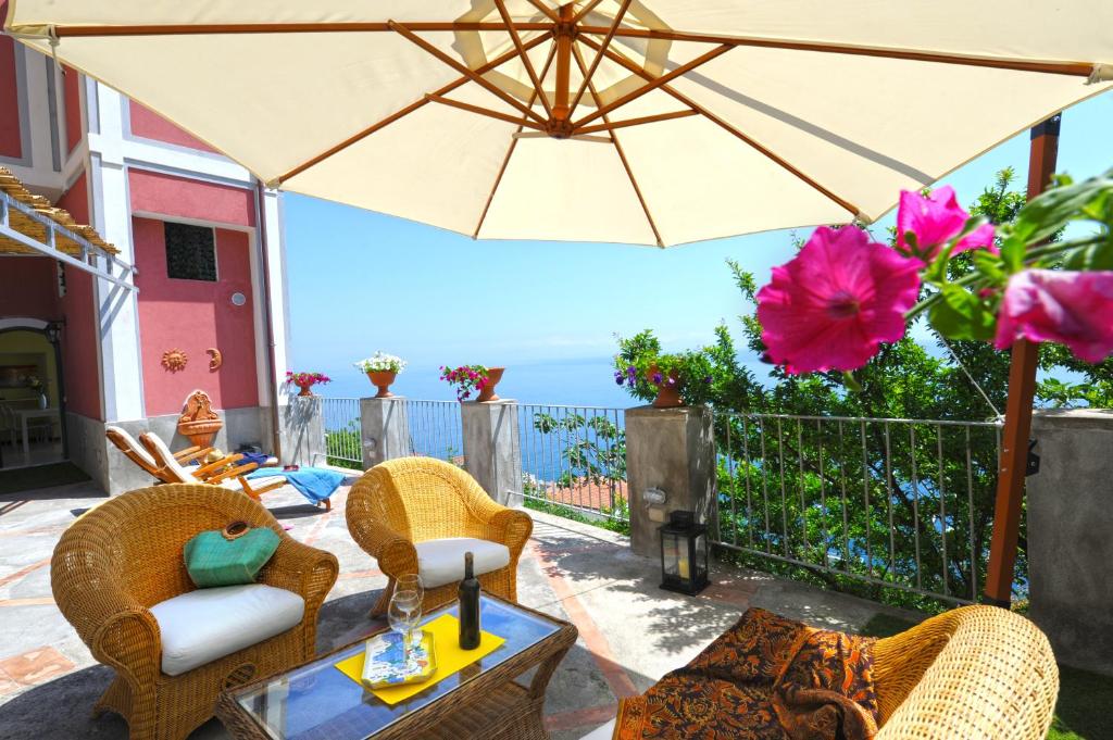 a patio with a table and chairs and an umbrella at Palazzo Rocco Villa Red Moon in Love in Praiano