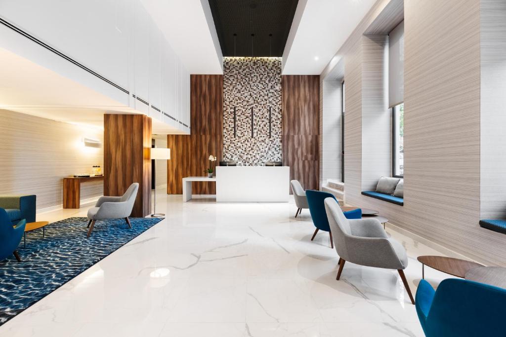 A reception lobby with a white desk, patterned feature wall and lounge seating.