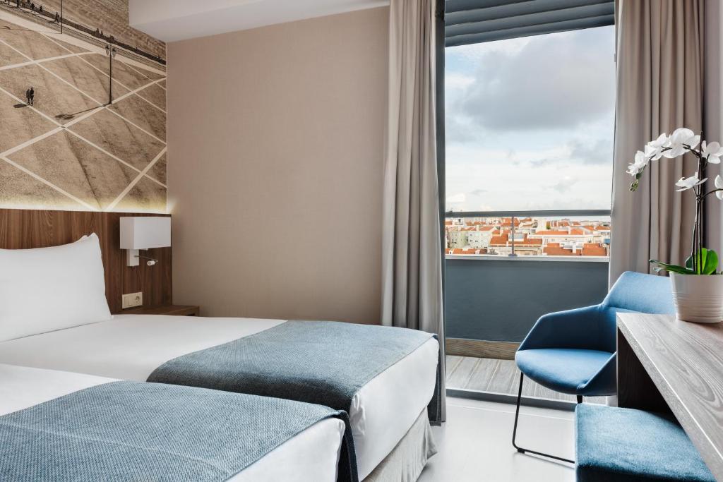 A twin room with a prominent glazed opening and rooftops beyond.