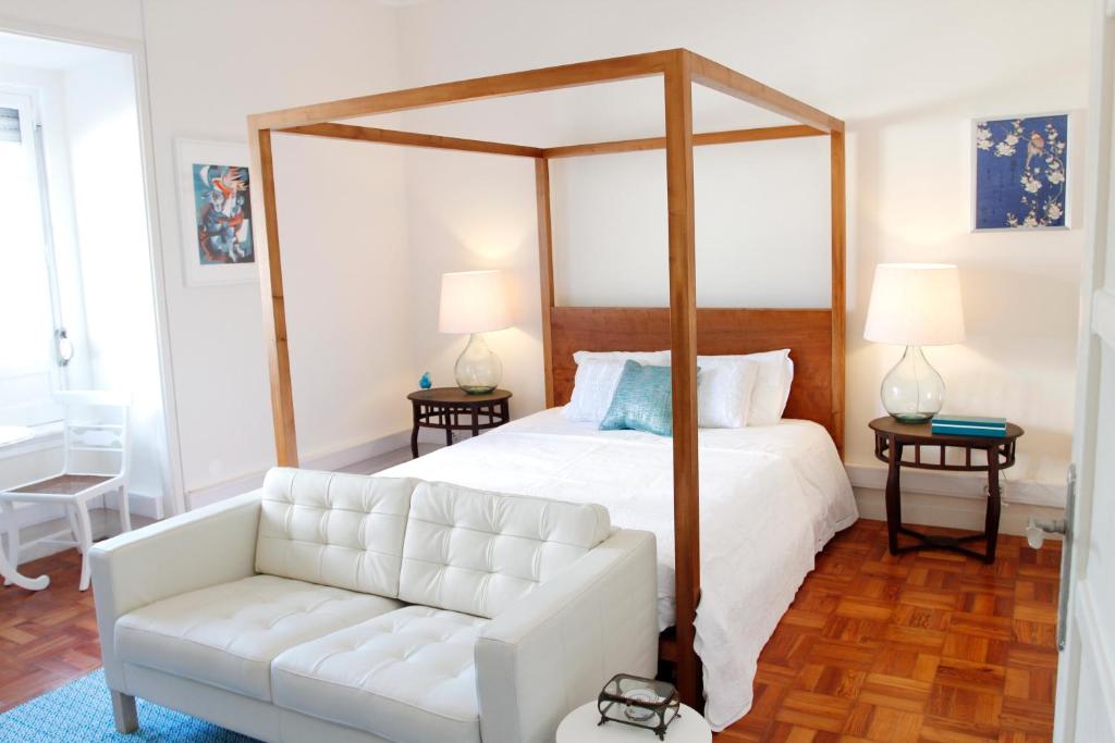 a white bedroom with a canopy bed and a white couch at Magnolia Guesthouse in Lisbon