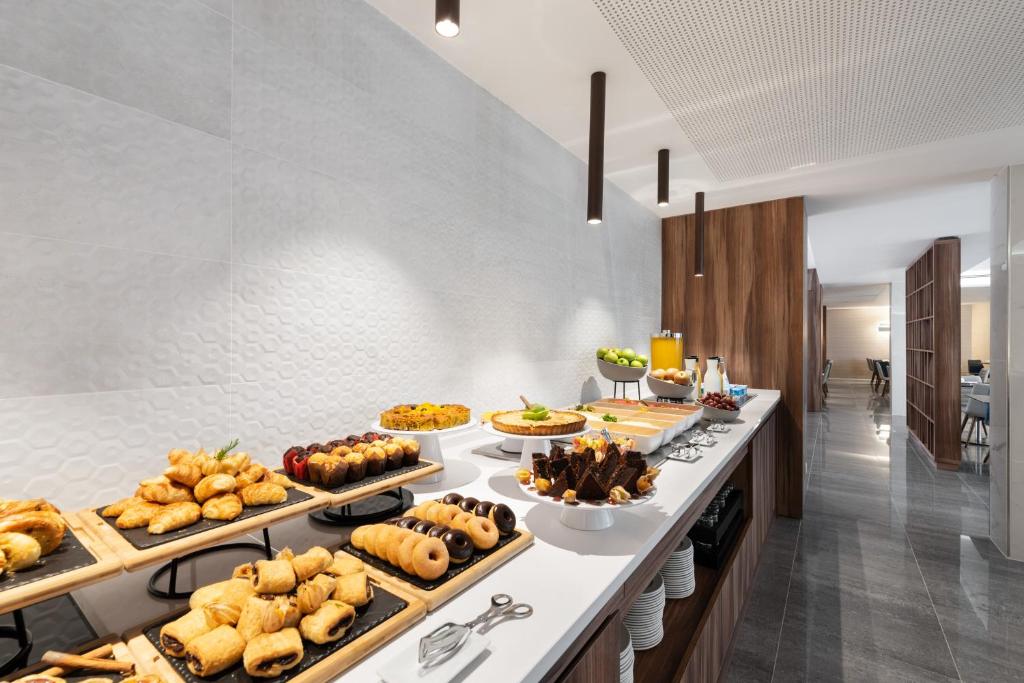 A long breakfast buffet lined with pastries, cakes, fruit and drinks.