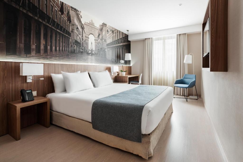 ein Hotelzimmer mit einem Bett und einem blauen Stuhl in der Unterkunft Exe Saldanha in Lissabon
