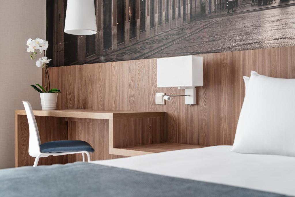 A compact in-room desk beside the bed, set against a city-street mural.