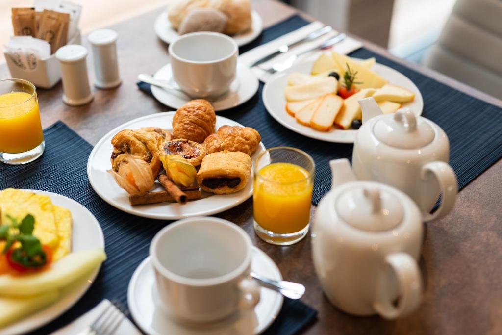 A breakfast table set with pastries, cheese, fruit, juice and tea.